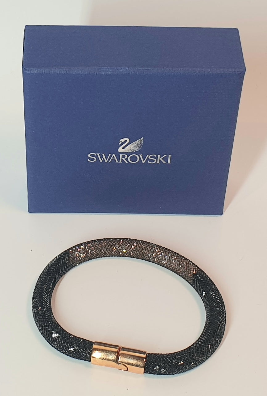 Black glittery bracelet with gold clasp in front of a Swarovski box