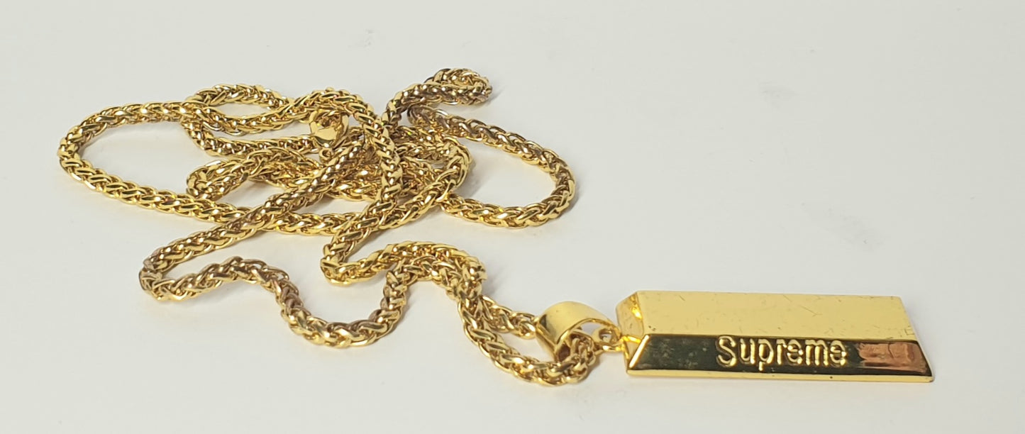Gold chain with a Supreme pendant on a light gray background