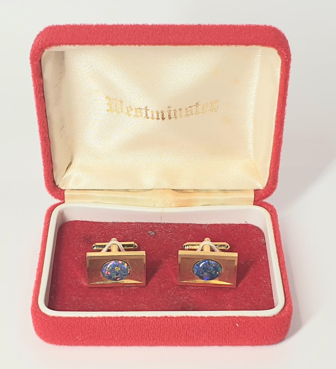 Gold cufflinks with blue gemstones in a red box with 'Westminster' branding.