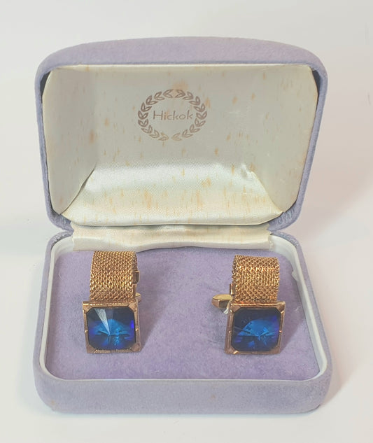 Gold cufflinks with blue stones in a Hickok box on a white background