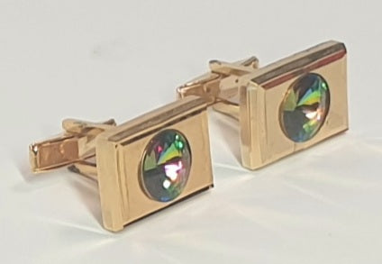 Gold cufflinks with a central gemstone on a white background