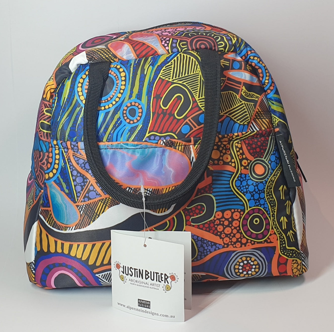 Justin Butler Lunch Tote, Colourful patterned bag with a Justin Butler tag on a light gray background