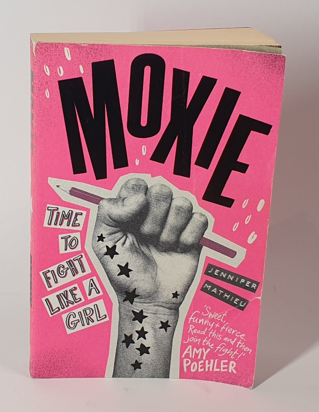 Book cover of 'Moxie' with a pink background and black text, featuring a fist holding a pen.