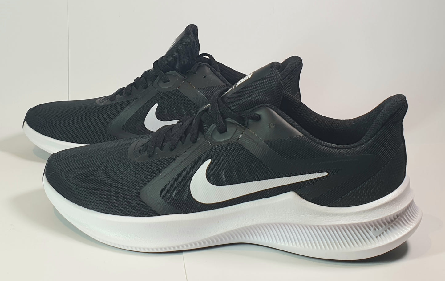 Black Nike running shoes with white soles on a light background