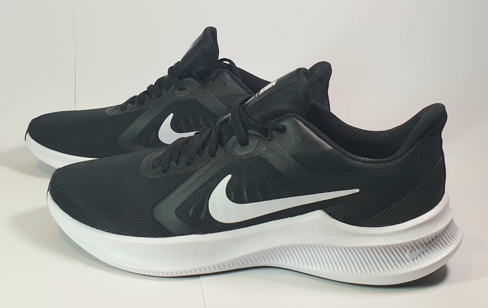 Black Nike running shoes with white soles on a light background