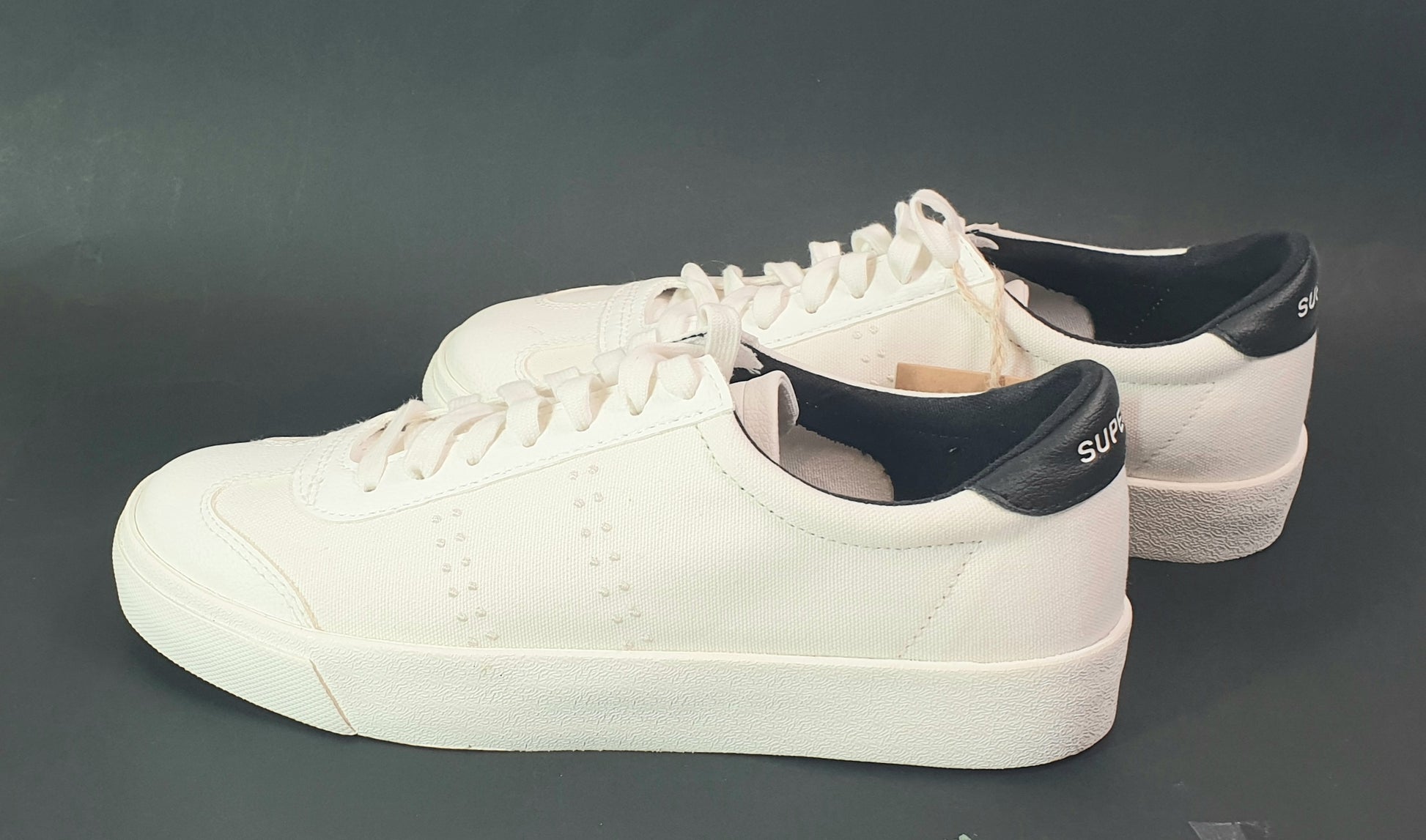 White sneakers with black accents on a dark gray background