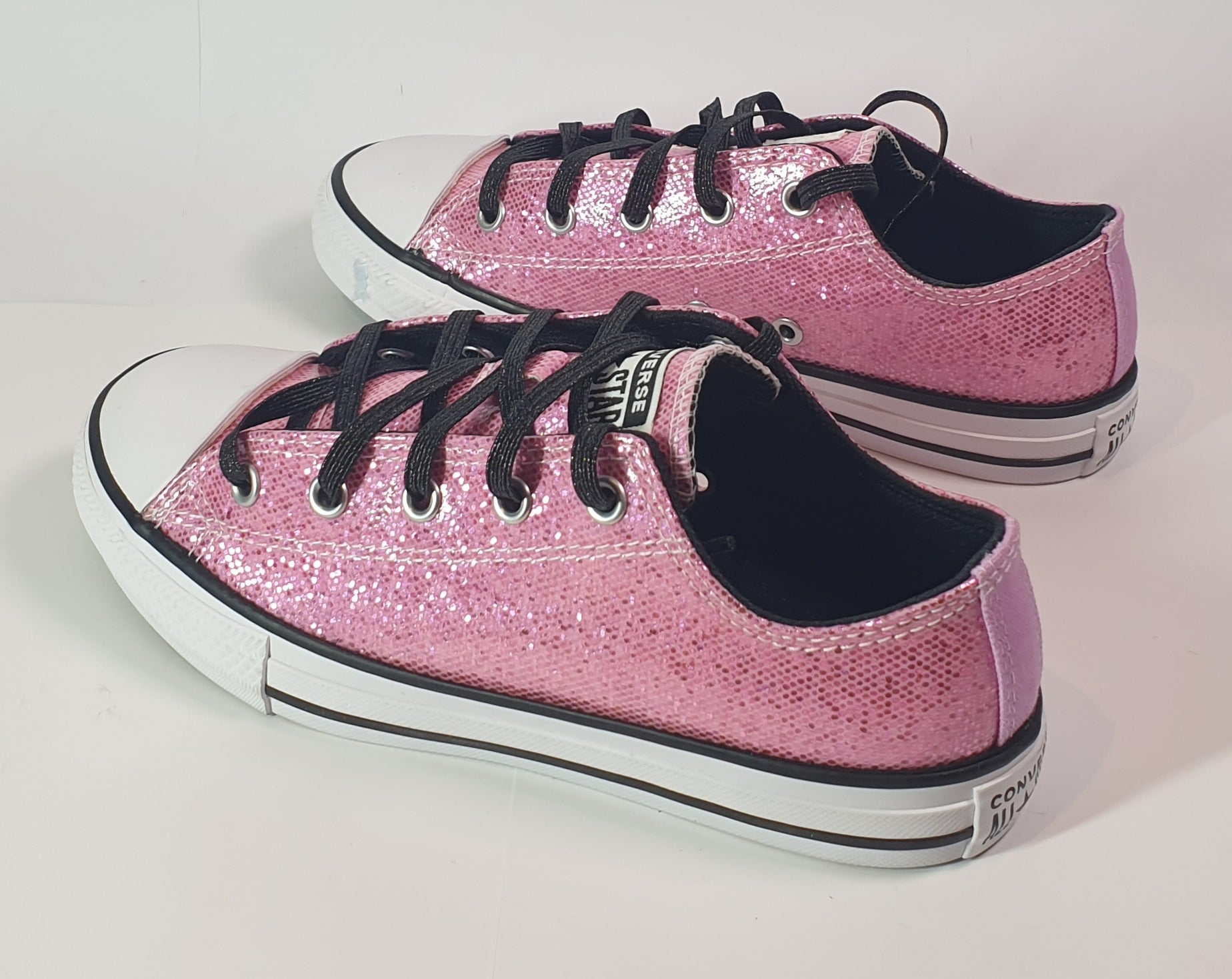 Pink glitter sneakers with black laces on a light gray background