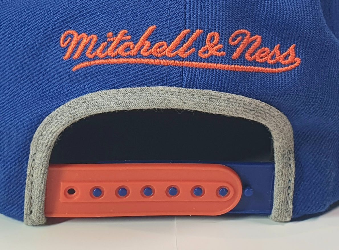 Blue cap with orange and white text 'Mitchell & Ness' on a white background
