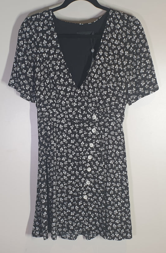 Black floral dress on a hanger against a white background