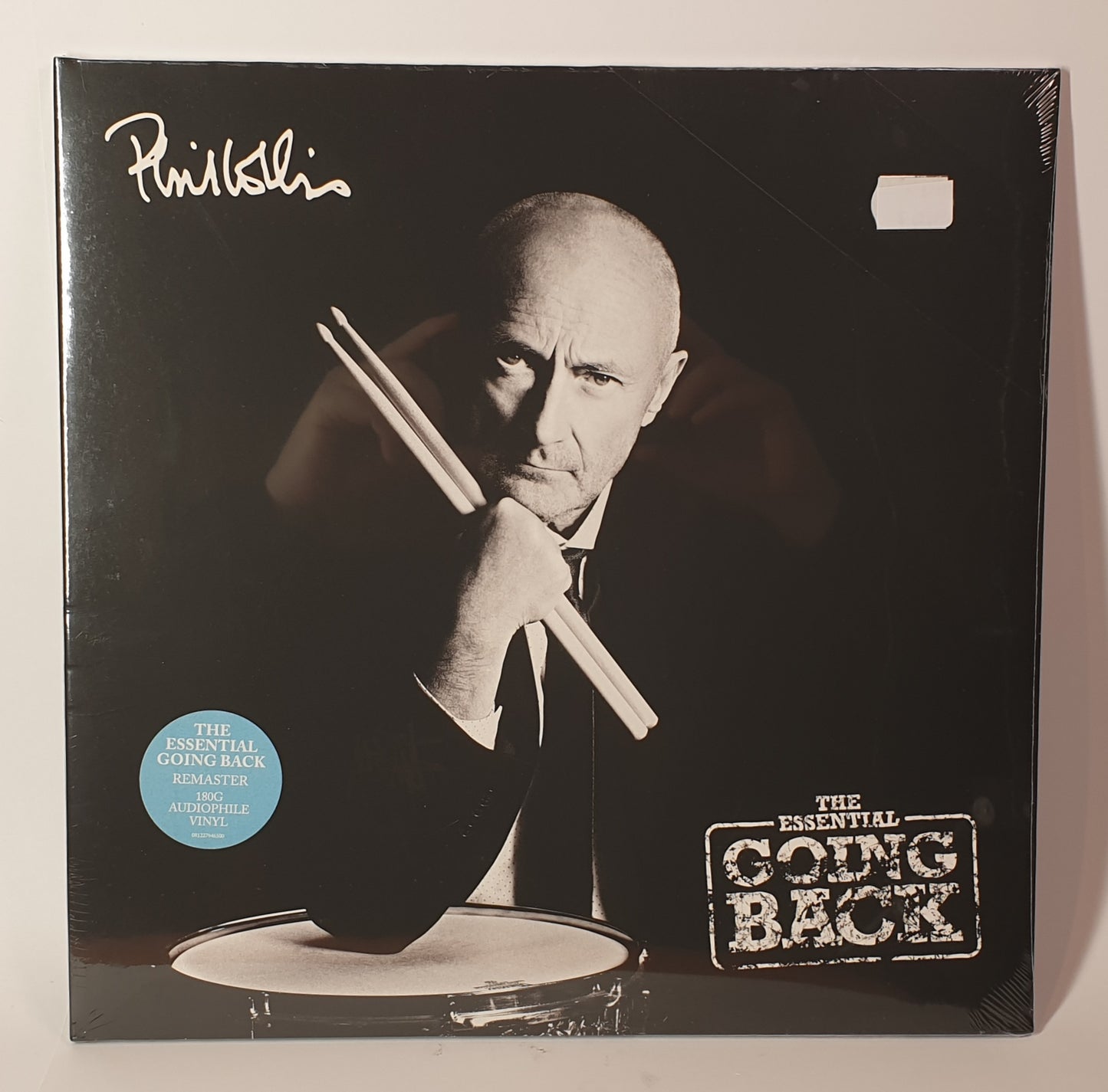 Vinyl record cover with a black and white photo of a person holding drumsticks, featuring the text 'The Essential Going Back'.