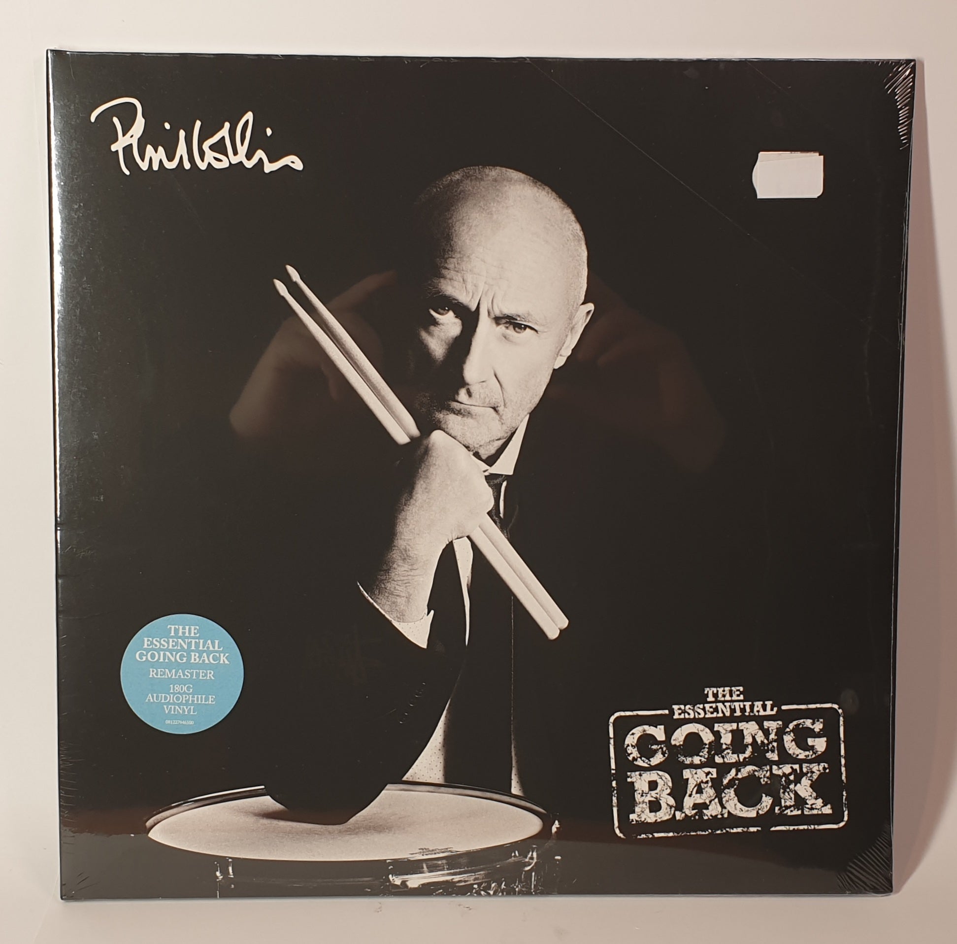 Vinyl record cover with a black and white photo of a person holding drumsticks, featuring the text 'The Essential Going Back'.