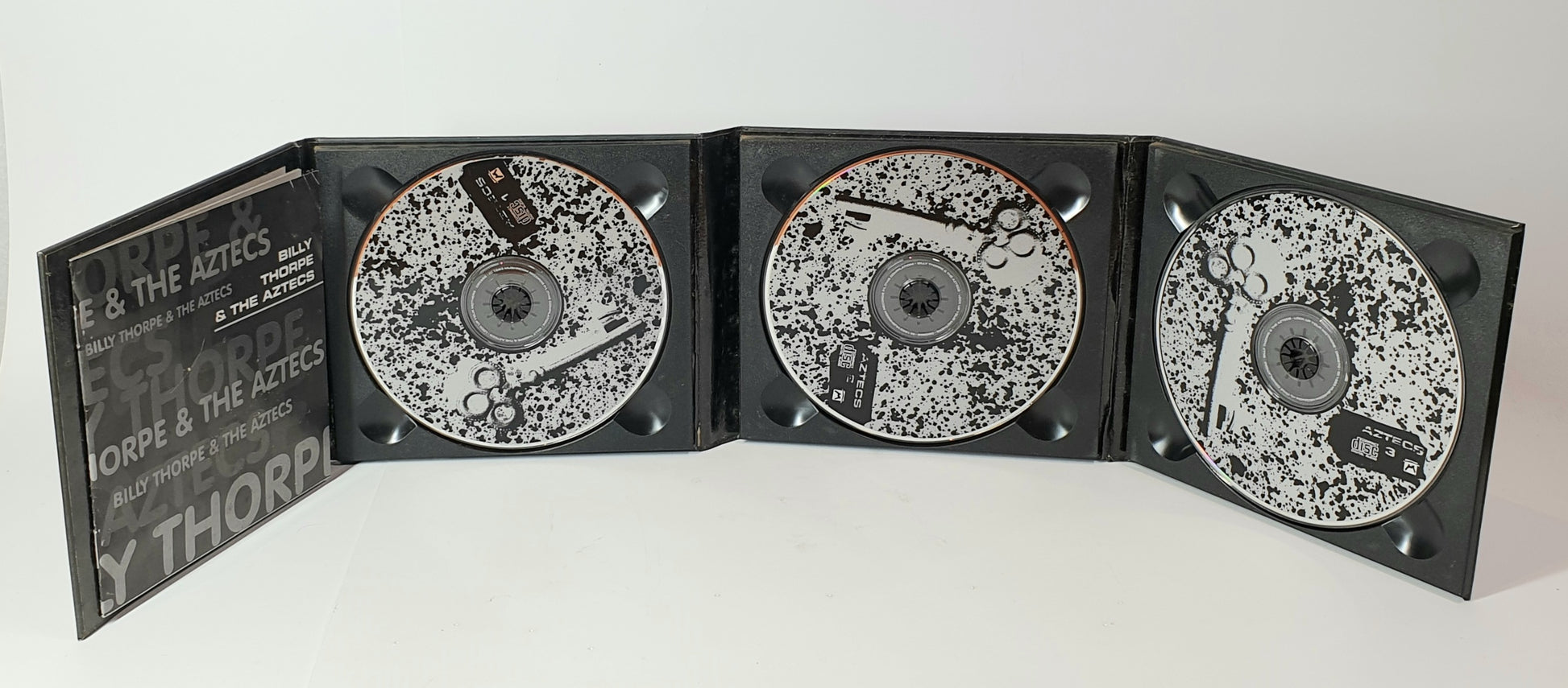 Black and white compact disc set with a branded case on a white background
