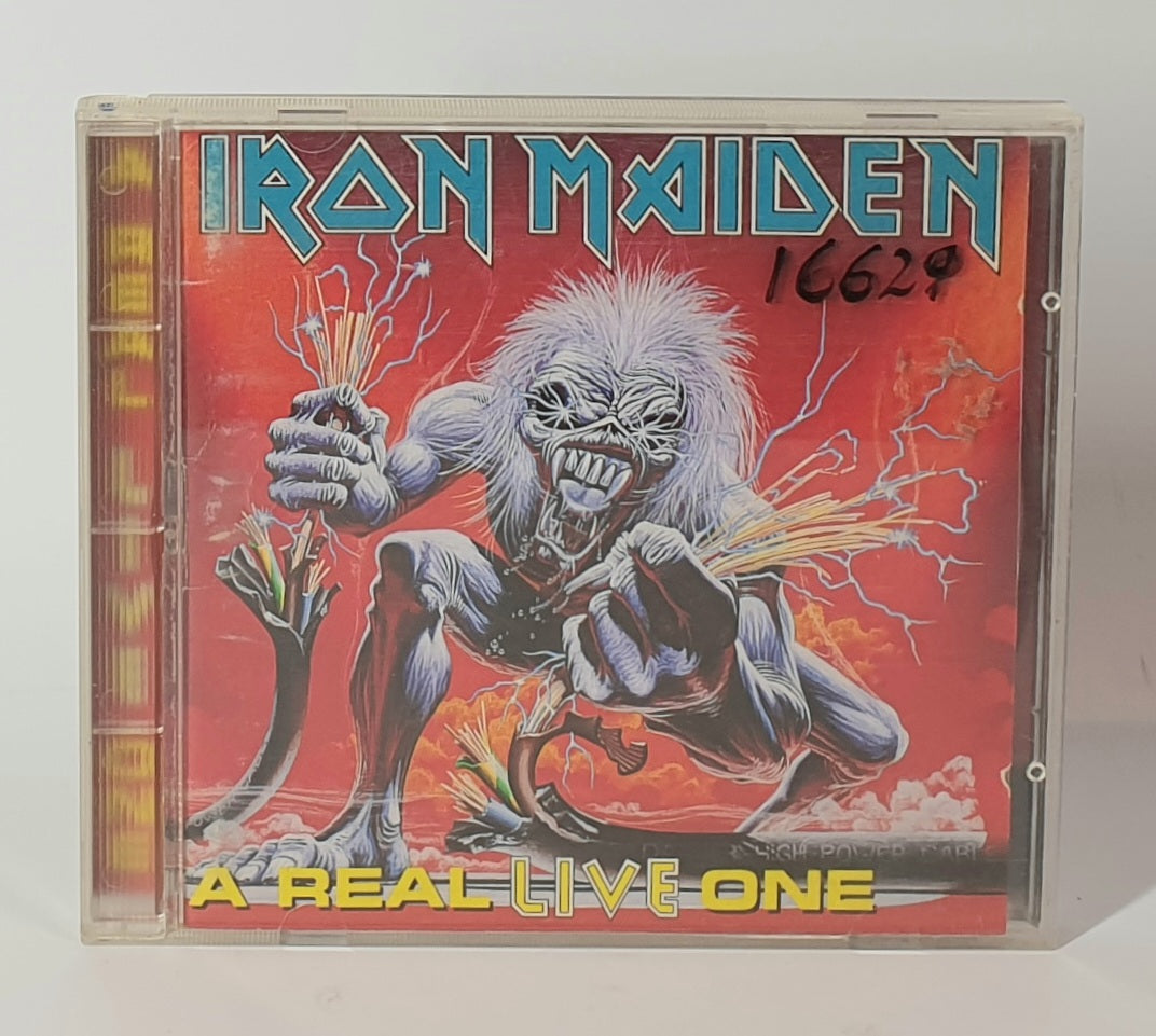 Iron Maiden album cover with a character holding electric guitars on a red background " A REAL LIVE ONE"