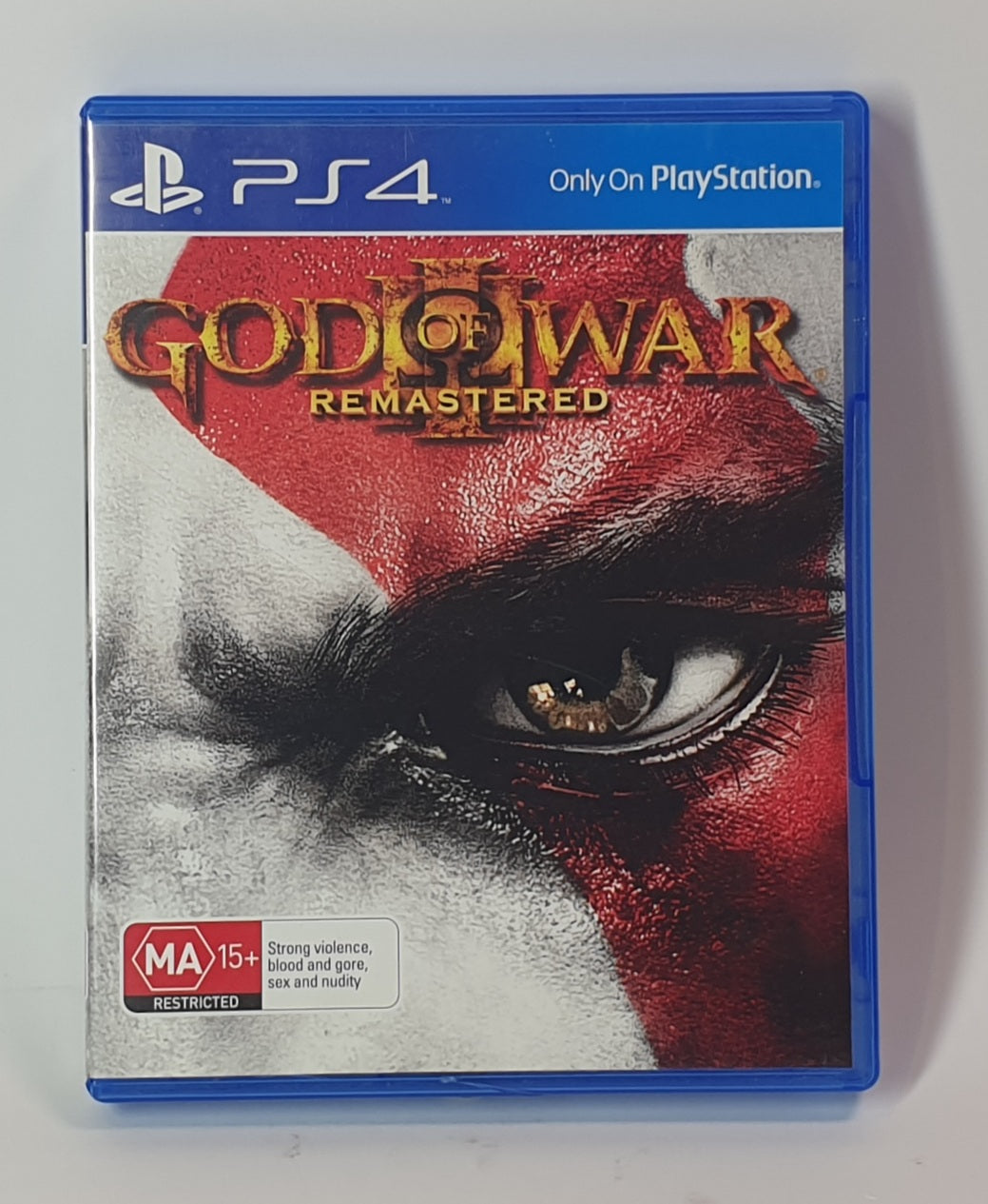 PlayStation 4 game case for 'God of War Remastered' with a close-up of an eye and red hair.
