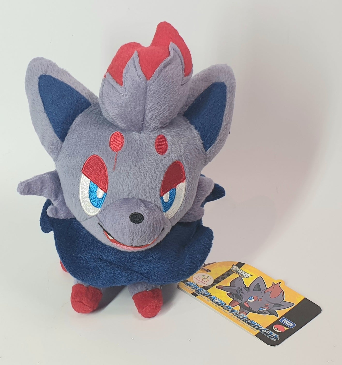 Plush toy of a character with red and blue accents on a white background