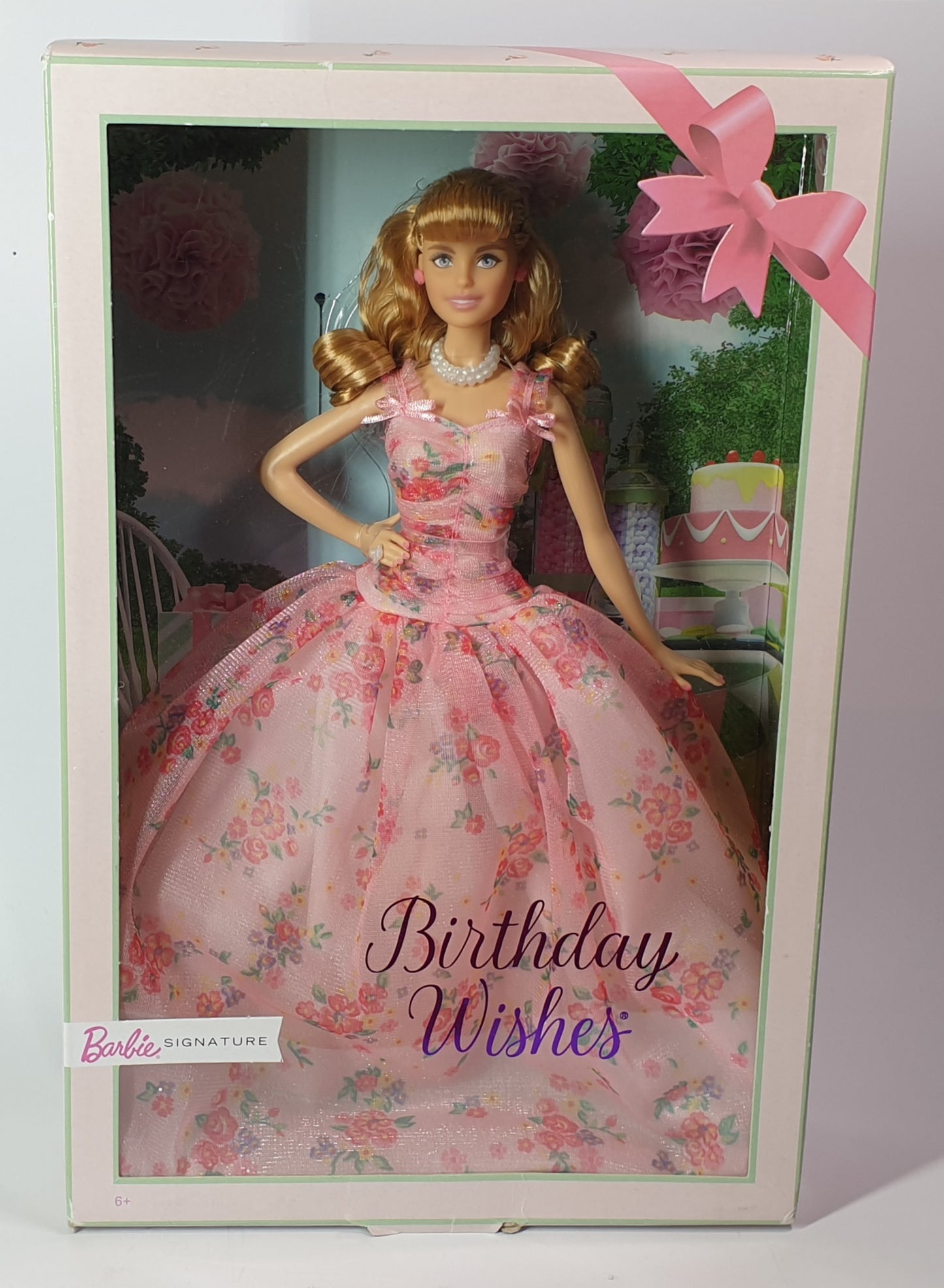 Barbie doll in a pink floral dress with 'Birthday Wishes' text in a decorative box.