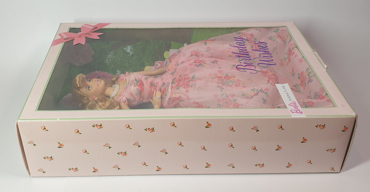 Barbie doll in a 'Birthday Wishes' dress inside a decorative box with floral patterns.